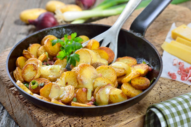 Fried potatoes with cheese Fried unpeeled baby potatoes with melted mountain cheese and bacon cubes fried potato stock pictures, royalty-free photos & images
