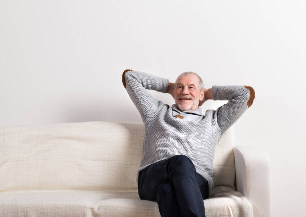 istock Senior man in gray sweater sitting on sofa, studio shot. 679286130
