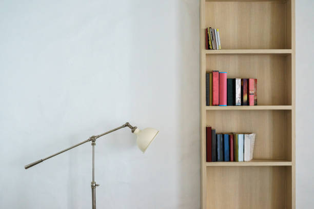 Metal lamp stand and wooden bookshelf with books stock photo