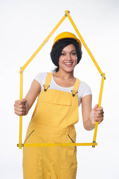 istock Builder wearing yellow helmet and overall showing a house frame 679298736