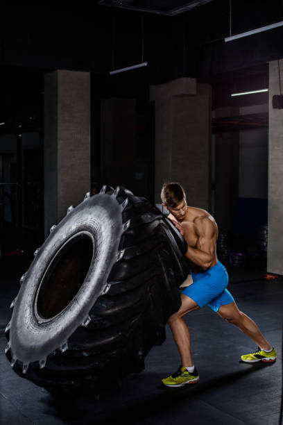 istock gym training - man flipping tire in gym 679305842