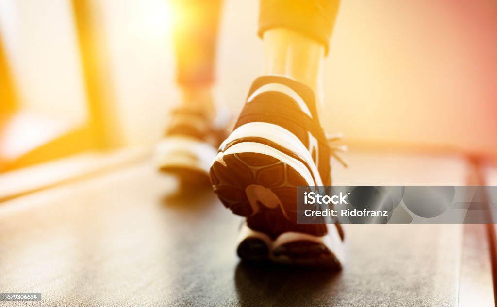 Woman exercising on treadmill Fitness girl running on treadmill at gym. Rear view of detail of feet of young woman wearing sneakers and running on treadmill. Fitness and healthy lifestyle concept. Treadmill Stock Photo