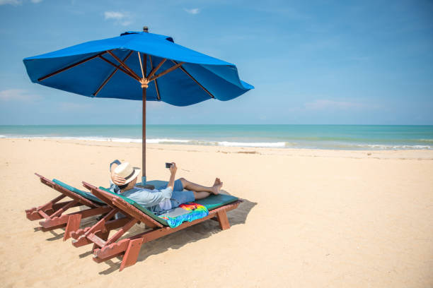 istock young man lying on beach bench and take photos 679307086