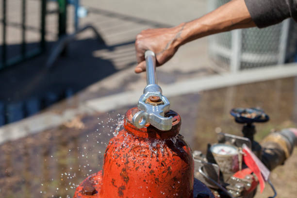 Leaking Fire Hydrant Spraying Water Being Closed with Wrench Leaking and Splashing Red Fire Hydrant Spraying Water Being Closed with Wrench fire hydrant stock pictures, royalty-free photos & images