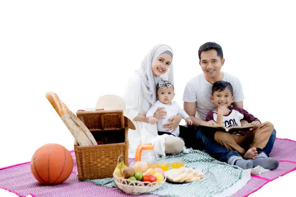 Image of Asian family smiling at the camera while picnicking together in the studio