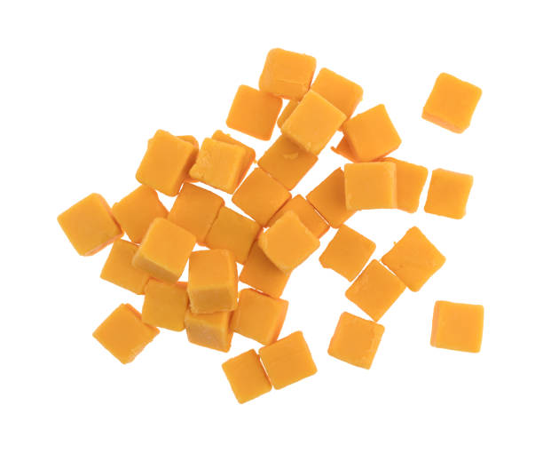 Cubed mild cheddar cheese on a white background Top view of a group of cubed mild cheddar cheese pieces isolated on a white background. cheddar cheese stock pictures, royalty-free photos & images