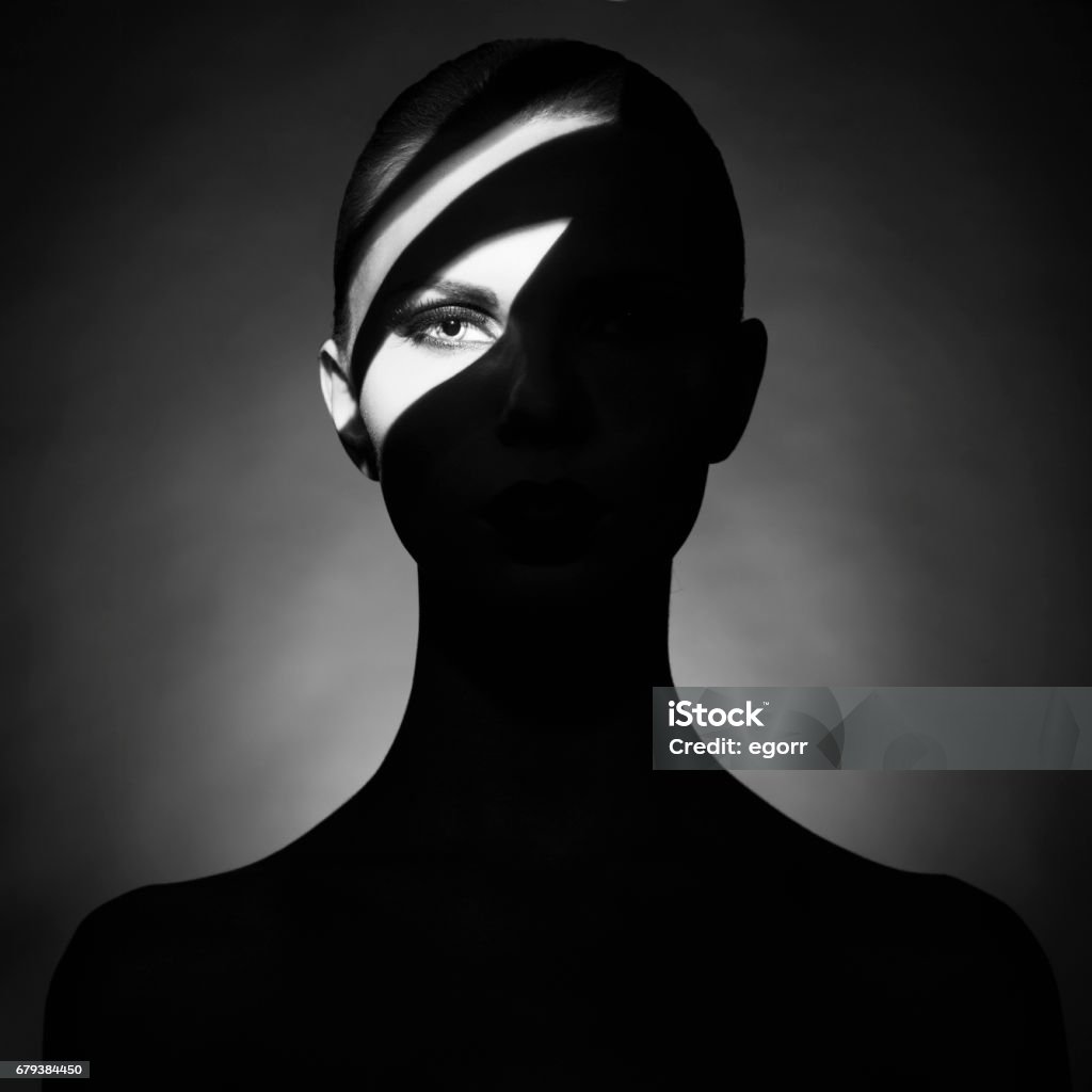 Fine art portrait of elegant lady with shadows on her face Fine art portrait of elegant lady with shadows on her face. Surrealist photo of young woman with artistic makeup Contrasts Stock Photo