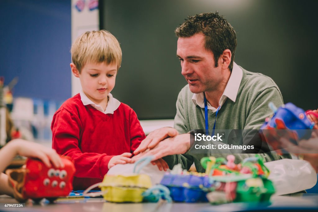 Building A Physics Project Teacher is helping his primary school student in the classroom with their STEM project. Teacher Stock Photo