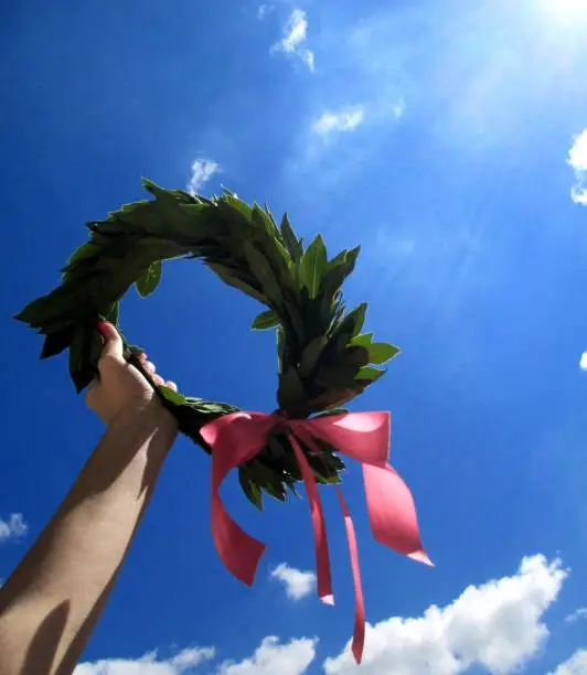Photo of Young Adult Woman Holding Laurel Wreath in her Hand