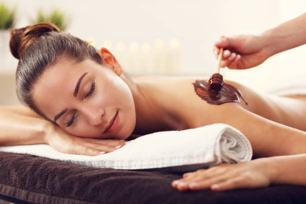 красивая женщина получать шоколадный массаж в спа - massaging chocolate spa treatment body стоковые фото и изображения