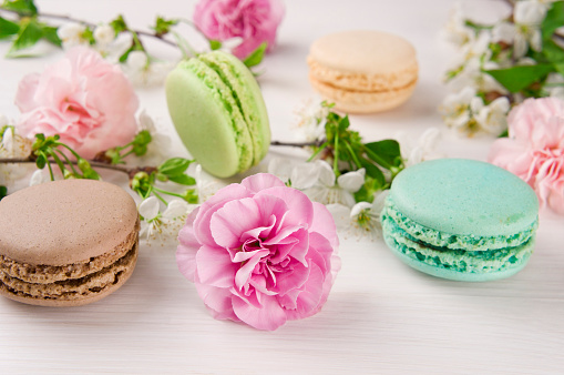 French macaroons. Turquoise, chocolate and green colors. Spring concept. Background with flowers and macaroons.