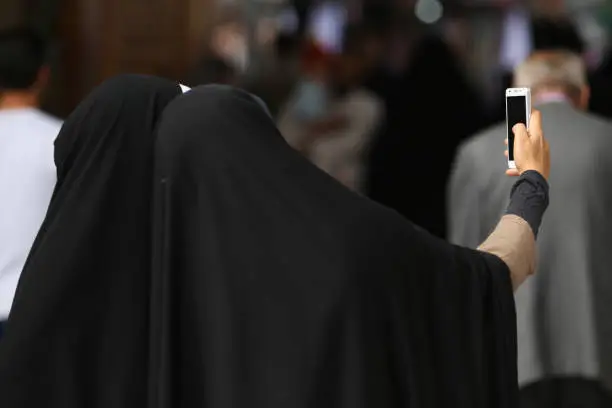 Muslim women with black hijabs posing for a selfie in a mosque in Qom, Iran