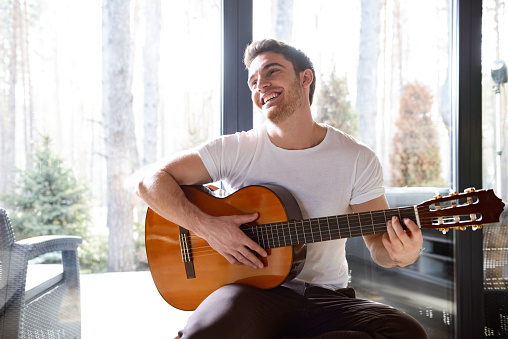 Portrait of handsome man with acoustic guitar smiling and looking away