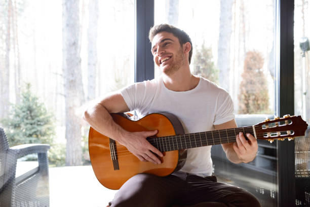smiling man with guitar Portrait of handsome man with acoustic guitar smiling and looking away solo performance stock pictures, royalty-free photos & images