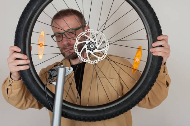 istock Bearded man puts the front wheel on the bicycle. 679482992