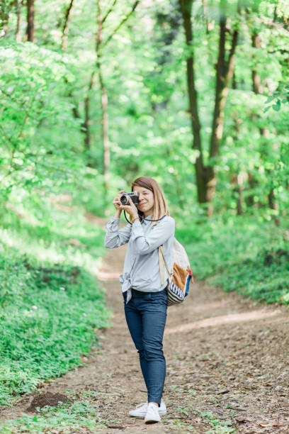 istock Young woman taking a photo in the forest 679483406