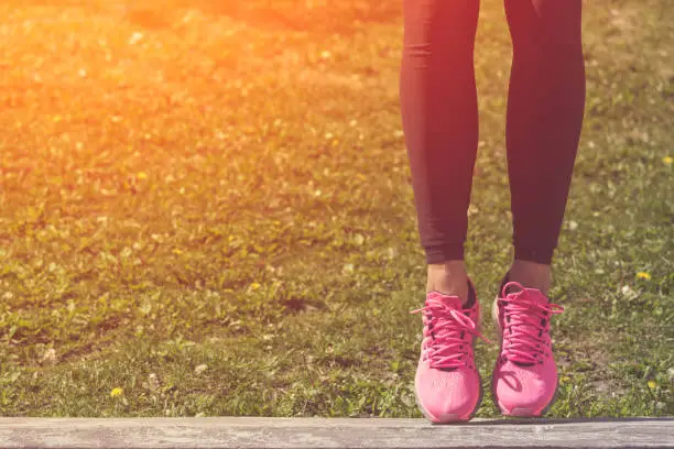 Close up of sportswoman legs in running shoes outdoors.