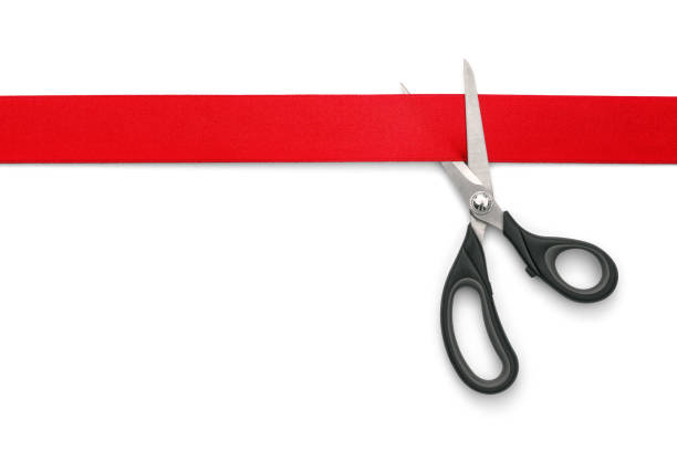 Red Ribbon Cutting Ceremony Scissors cutting red ribbon or tape against white background -Clipping Path metallic red chrome pattern stock pictures, royalty-free photos & images
