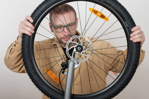 istock Bearded man puts the front wheel on the bicycle. 679484936