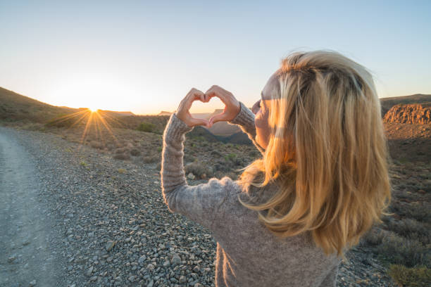 istock Young woman framing sunrise with heart 679486586