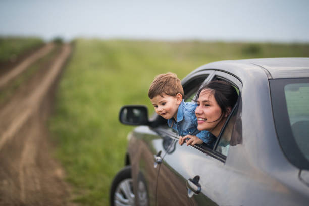 Mother and son looking through the winodw of the car on their roadtrip in nature