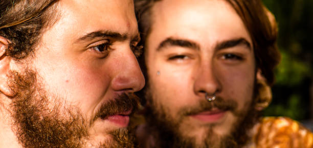 Face portrait of a young gay couple, photographed with natural light of the late afternoon. Selective focus. Face portrait of a young gay couple, photographed with natural light of the late afternoon. Selective focus. casamento stock pictures, royalty-free photos & images