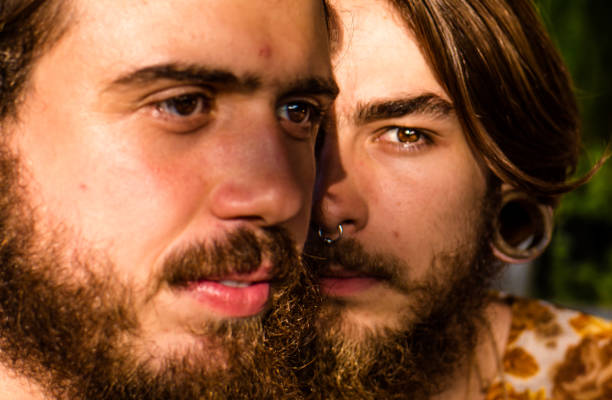 Face portrait of a young gay couple, photographed with natural light of the late afternoon. Selective focus. Face portrait of a young gay couple, photographed with natural light of the late afternoon. Selective focus. casamento stock pictures, royalty-free photos & images