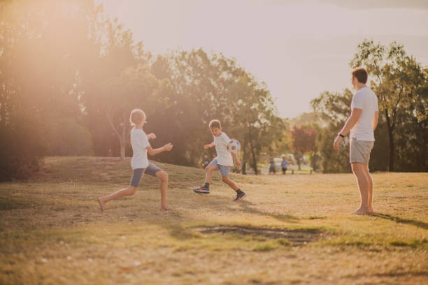 ragazzi che giocano a calcio nel parco - kick off soccer player soccer kicking foto e immagini stock