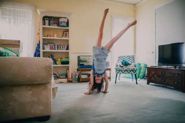 Little girl doing gymnastics in the living room of her family home.