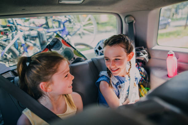 Sisters Sitting in Their Family Car Sisters sitting in the back of their family car, talking to one another and laughing. bicycle rack photos stock pictures, royalty-free photos & images