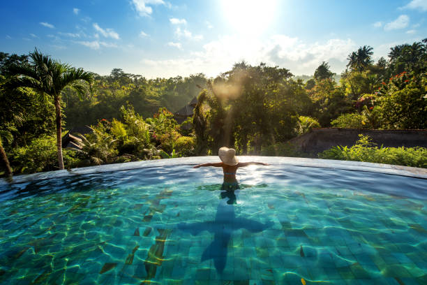 happiness concept. Woman sunbathing in infinity swimming pool at luxurious resort stock photo