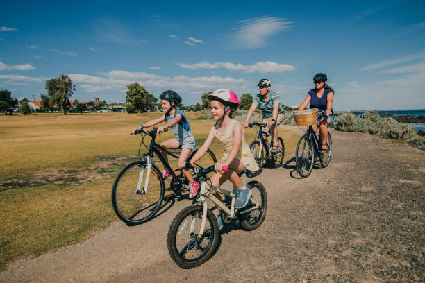 Family of Four Cycling in the Park Family of four cycling in the park on a sunny day in Australia. cycling helmet photos stock pictures, royalty-free photos & images