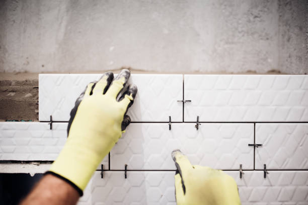 istock Professional industrial worker installing small ceramic tiles in bathroom during renovation works 679511802