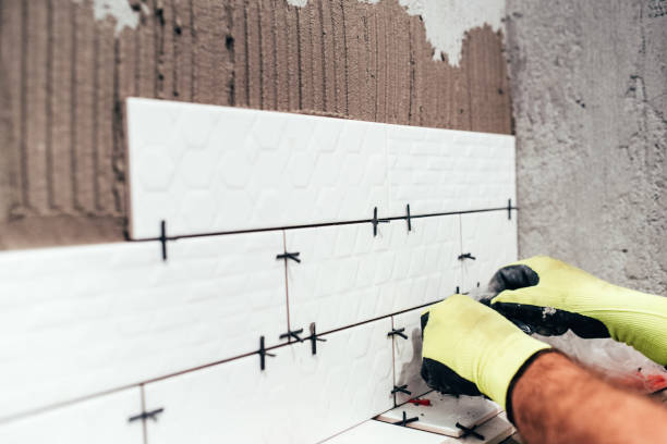 istock Renovation in progress. Industrial worker installing bathroom ceramic tiles 679511850