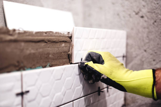 istock tiler applying ceramics with adhesive and using plastic spacers in interior design manufacturing 679511898