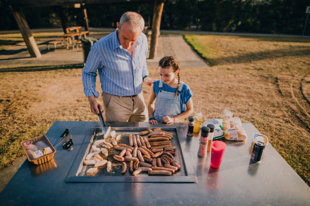 istock Helping Dad Cook Sausages on the BBQ 679512080