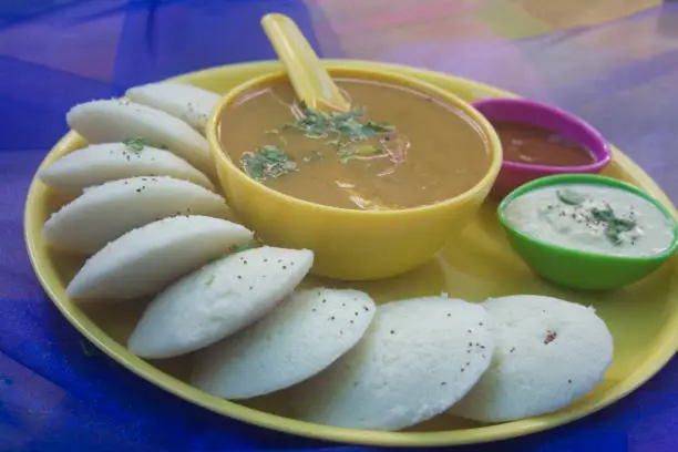 Photo of Idli with Sambar and coconut chutney on violet background