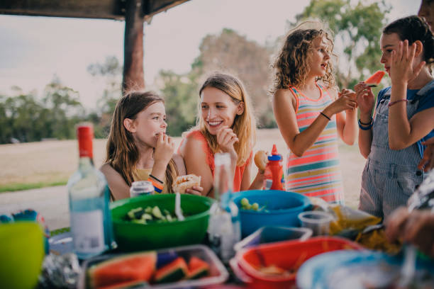 Fun at a Family BBQ Sitting at a picnic table in the park at a family BBQ. barbecue social gathering photos stock pictures, royalty-free photos & images