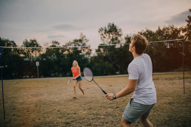 jeune couple badminton jouant dans le parc - raquette de badminton photos et images de collection