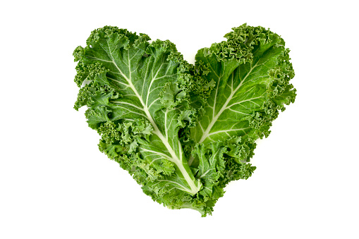 closeup of some leaves of kale forming a heart on a white background
