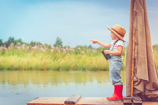 Little girl looking through binoculars from raft