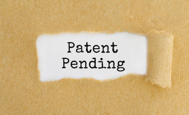istock Text Patent Pending appearing behind ripped brown paper. 679521218