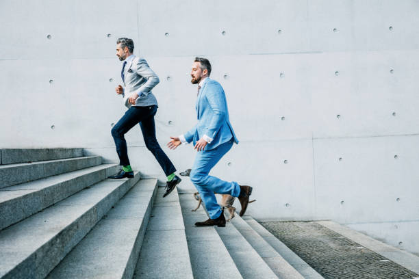 istock Two Businessmen running up on steps with dog 679524392