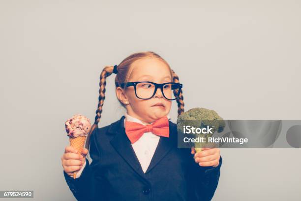 Young Female Nerd Holds Ice Cream And Broccoli Stock Photo - Download Image Now - Choice, Child, Decisions