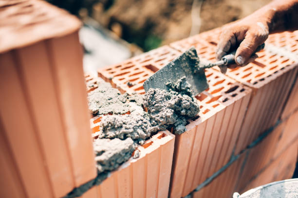 istock Industrial worker using trowel and tools for building exterior walls with bricks and mortar 679524852