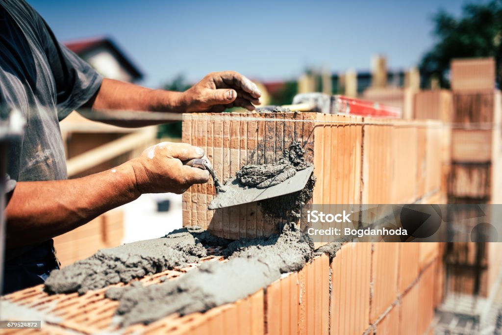 Industrial construction worker using spatula and trowel for building walls with bricks and mortar Bricklayer Stock Photo