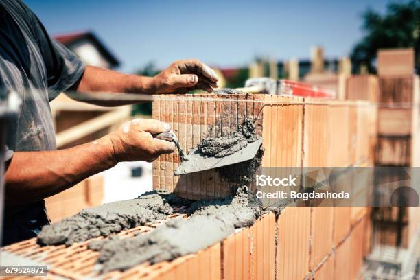 Industrial Construction Worker Using Spatula And Trowel For Building Walls With Bricks And Mortar Stock Photo - Download Image Now