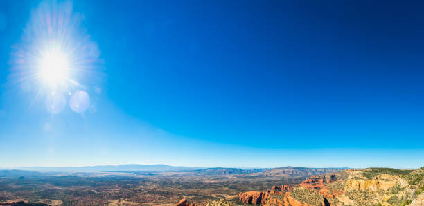 Hot sun flaring in clear blue desert skies over the iconic red rock buttes and ponderosa forests of Sedona, Arizona, USA.