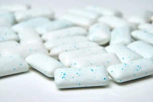 Photo of Chewing gum spilled out on white background with low depth of field - macro shot.