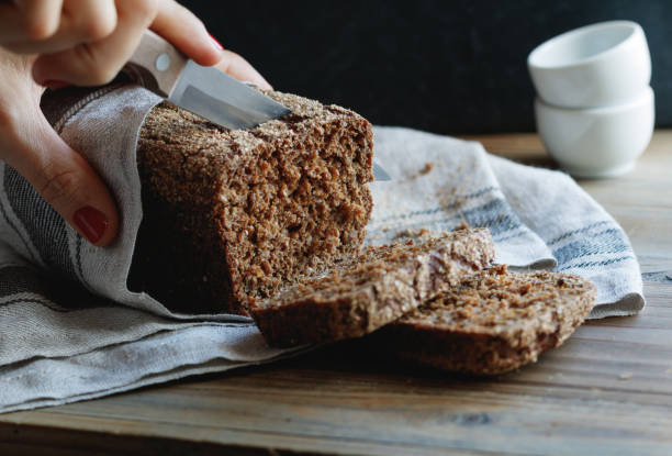 istock The girl cuts whole-wheat rye bread on a wooden table. 679552902